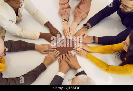 Gruppo multiculturale di persone che tengono le mani sulla Bibbia e pregano insieme Foto Stock