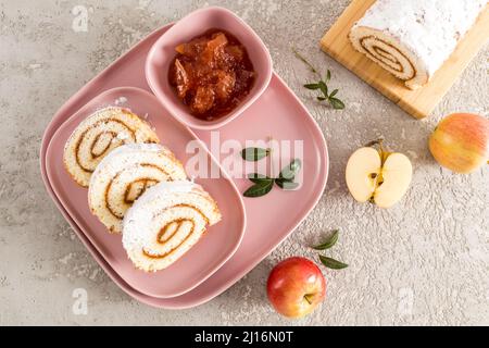 le mele fresche e i pezzi di pan di spagna fatti in casa rotolano in zucchero a velo su un vassoio di ceramica rosa vista dall'alto Foto Stock