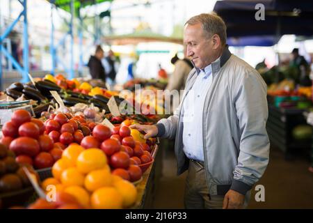 Uomo che acquista peperoni in gregrocery Foto Stock