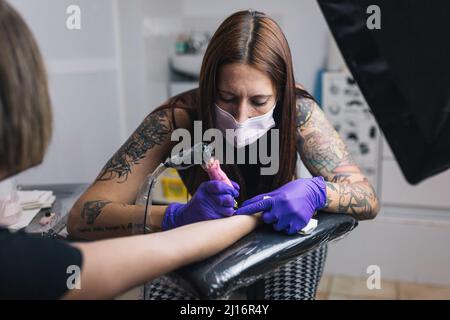 Ragazza maestra di tatuaggi caucasica che lavora con una macchina per  tatuaggio in studio, ripresa verticale media. Foto di alta qualità Foto  stock - Alamy