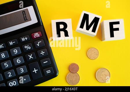 Texte sur RMF for Retirement Mutual Fund realizzato in blocchi di legno con pila di monete che fuoriescono dalla banca di porcellini di vetro sul tavolo con spazio di copia. Fiscalità, AN Foto Stock