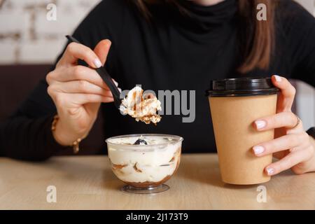 La donna mangia un dessert cremoso e beve caffè a colazione in caffetteria. Cibo e bevande foto. Buon concetto di mattina. Foto Stock