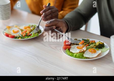 Colazione sana. Uomo nero e Donna mangiare cibo gustoso in cucina Foto Stock