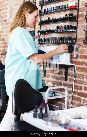 Ritratto di giovane donna professionale chiodo maestro in piedi al posto di lavoro per salone Foto Stock