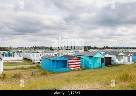 Capanne sulla spiaggia e sito di roulotte mobile sul lungomare di North Beach Heacham, un villaggio costiero nel Norfolk occidentale, Inghilterra, verso South Beach Hunstanton Foto Stock