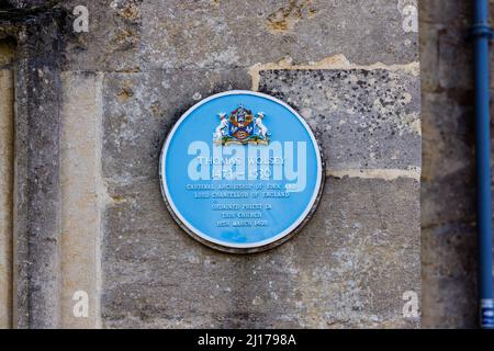 Targa blu sul muro della chiesa di San Pietro del 15th secolo che commemora l'ordinazione di Thomas Wolsey nel 1498, High Street, Marlborough, Wiltshire Foto Stock