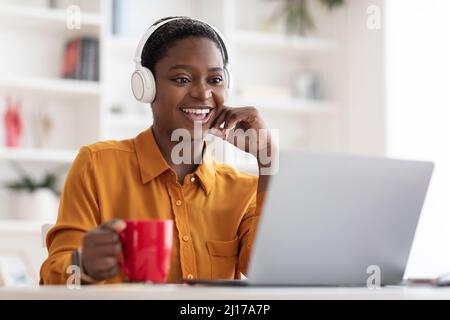 Felice donna afroamericana che guarda il video su un portatile Foto Stock
