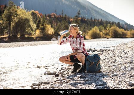 Austria, Alpi, donna su un viaggio escursionistico avente una interruzione in corrispondenza di un ruscello Foto Stock