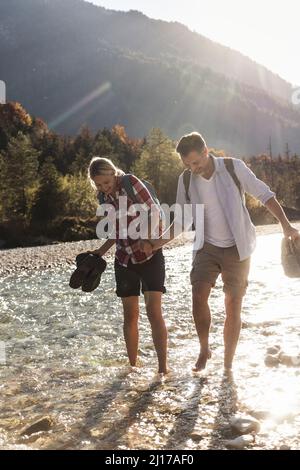 Austria, Alpi, giovane su un viaggio escursionistico guadare in un ruscello Foto Stock