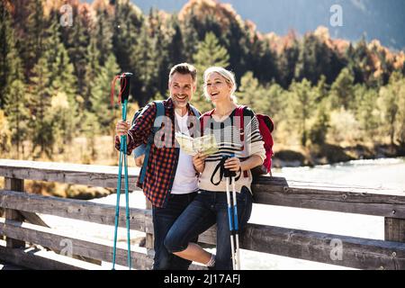 Austria, Alpi coppia felice su una escursione con la mappa su un ponte Foto Stock