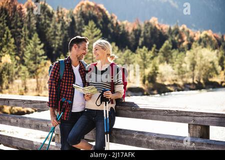 Austria, Alpi coppia felice su una escursione con la mappa su un ponte Foto Stock