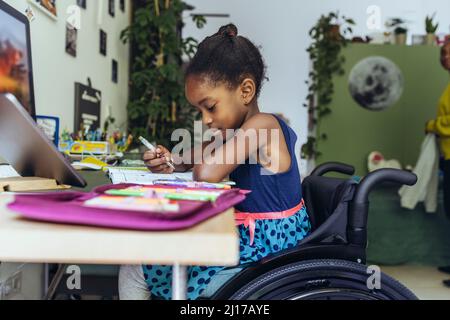 Ragazza disabili che studia alla scrivania in camera da letto Foto Stock