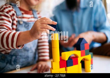 Casa di costruzione ragazzo con blocchi giocattolo da padre a casa Foto Stock