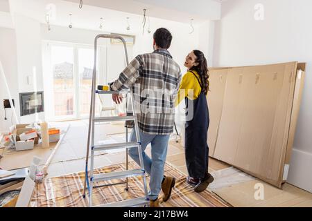 Giovane coppia che guarda il soggiorno in fase di ristrutturazione all'interno di una nuova casa Foto Stock