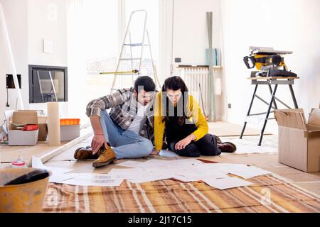Giovane coppia che esamina i piani di pavimento in nuova casa Foto Stock