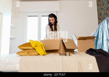 Giovane donna che disimballo scatole di cartone e riposizionamento in casa nuova Foto Stock