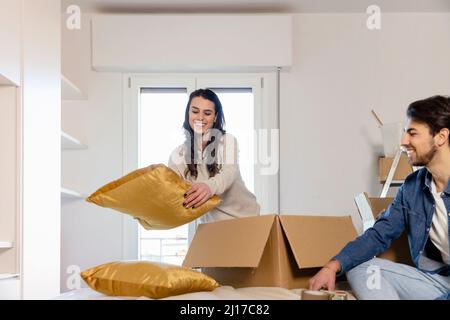 Giovane coppia disimballaggio scatole di cartone in camera da letto e il passaggio in nuova casa Foto Stock