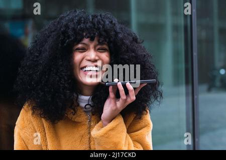 Donna felice che invia messaggi vocali tramite smartphone Foto Stock