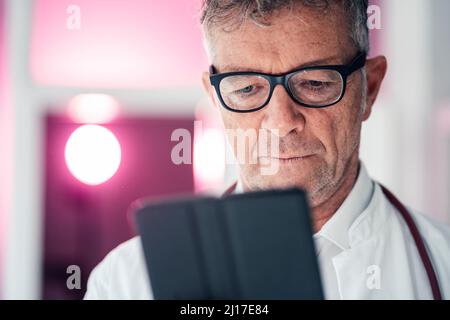 Medico generico che utilizza un computer tablet in clinica Foto Stock