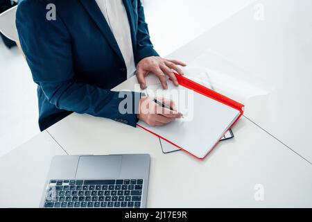 Uomo d'affari che scrive su archivio con la penna in ufficio Foto Stock
