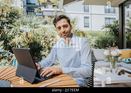 Freelance con computer tablet sul tavolo nel cortile posteriore Foto Stock