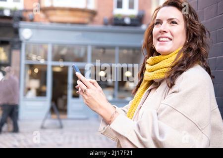 Felice giovane donna che tiene il cellulare Foto Stock