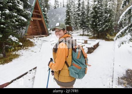 Donna che guarda oltre spalla in piedi sulla neve nella foresta invernale Foto Stock