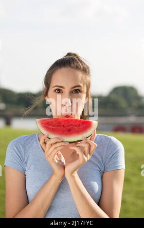 Giovane donna con fetta di cocomero in giornata di sole Foto Stock