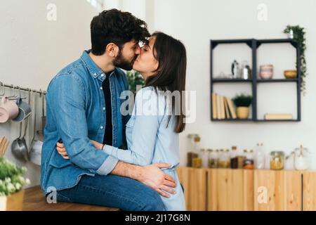Una coppia affettuosa si bacia in cucina Foto Stock