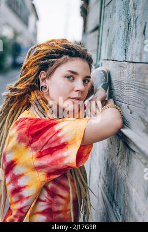 Giovane donna con dreadlock appoggiata su muro di legno Foto Stock