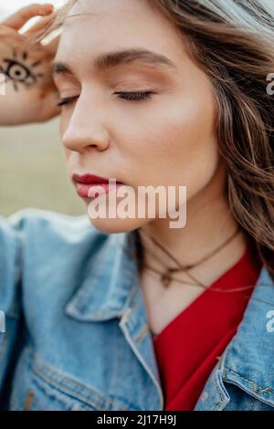 Donna con occhi chiusi indossando una giacca in denim Foto Stock