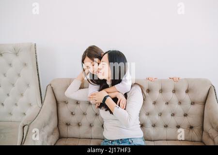 Madre che abbraccia la figlia nel soggiorno Foto Stock