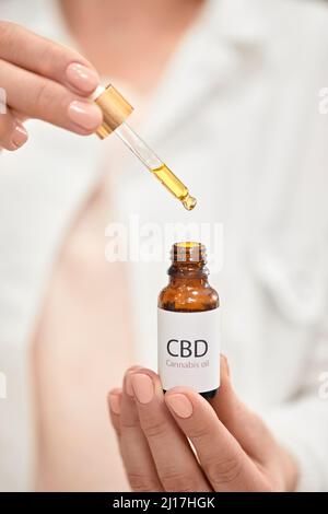 Farmacista che tiene una bottiglia di olio di cannabis in farmacia Foto Stock