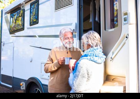 Felice coppia senior tenendo la tazza di caffè parlare con la donna da casa a motore Foto Stock