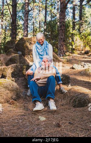 Coppia anziana felice seduta sulle rocce nella foresta Foto Stock