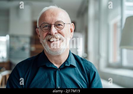 Uomo di lavoro anziano felice che indossa occhiali in ufficio Foto Stock