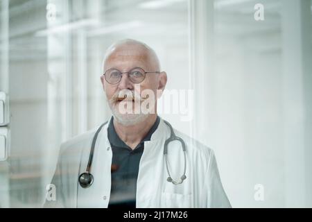Medico senior con baffi indossare occhiali presso la clinica medica Foto Stock