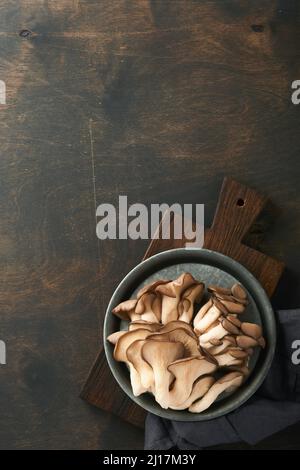 Funghi di ostrica freschi. Stira una vecchia ciotola di deliziosi funghi ostrica biologici su un vecchio sfondo di legno, vista dall'alto con spazio per il testo. Foto Stock