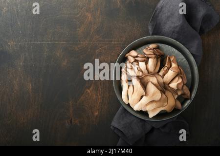 Funghi di ostrica freschi. Stira una vecchia ciotola di deliziosi funghi ostrica biologici su un vecchio sfondo di legno, vista dall'alto con spazio per il testo. Foto Stock