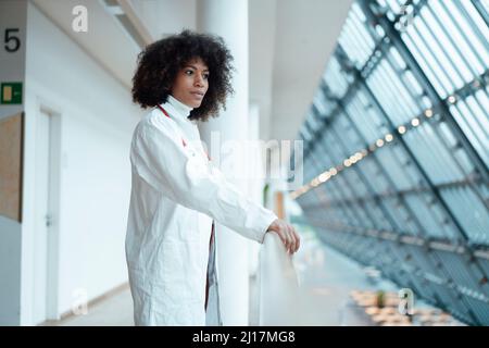 Medico contemplativo in piedi in corridoio all'ospedale Foto Stock