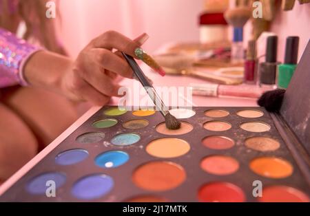 Persona non binaria che tiene il pennello sulla tavolozza delle ombre degli occhi Foto Stock