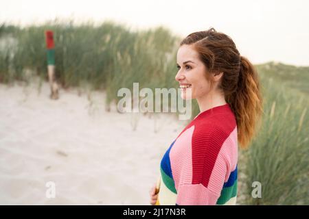 Sorridente donna rossa in piedi accanto al prato Foto Stock