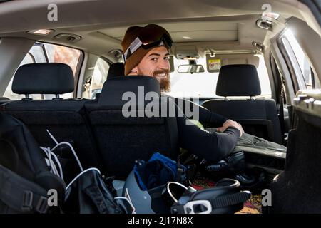 Sorridente ragazzo seduto in macchina guardando sopra la spalla Foto Stock