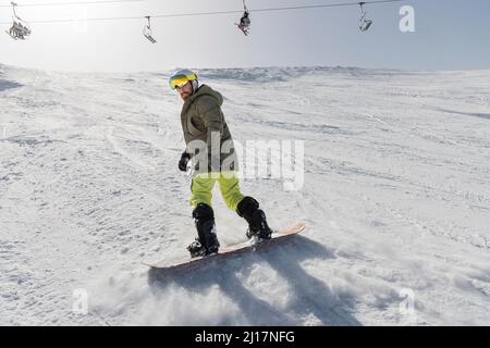 Snowboarding giovane uomo sulla montagna innevata Foto Stock