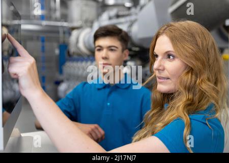 Il tecnico IT spiega l'utilizzo del dispositivo touch screen al partecipante in fabbrica Foto Stock