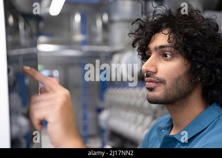 Il tecnico utilizza il dispositivo touch screen della macchina in fabbrica Foto Stock