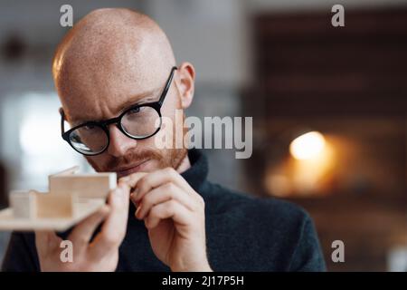 Uomo d'affari che esamina il modello in legno in ufficio Foto Stock