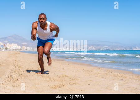 Sportivo che corre in spiaggia nelle giornate di sole Foto Stock