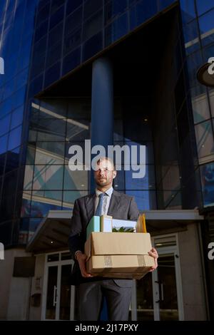 Uomo d'affari con scatola di effetti personali in città Foto Stock