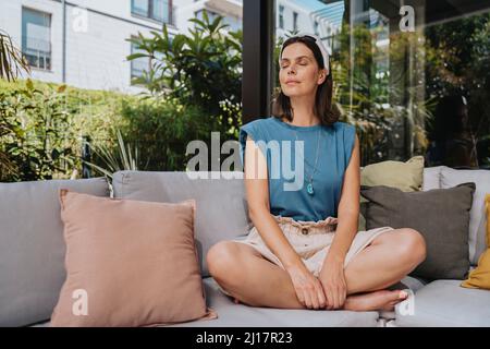 Donna con frequenza delle onde cerebrali indossabile sulla testa rilassante in giardino, Colonia, NRW, Germania Foto Stock